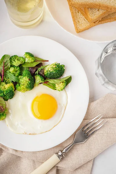 Plate Tasty Fried Egg Broccoli Spinach Light Background — Stock Photo, Image