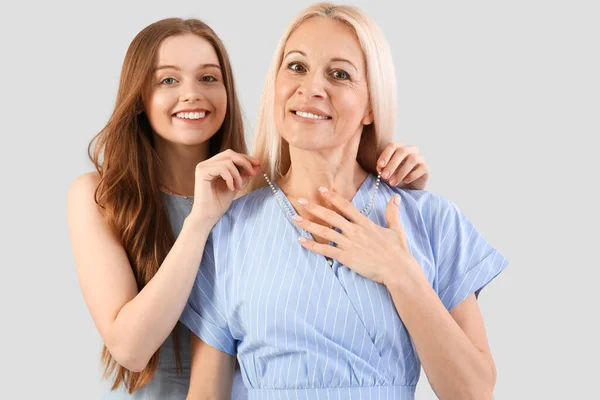 Young Woman Putting Necklace Her Mother Neck Grey Background — Stock Photo, Image