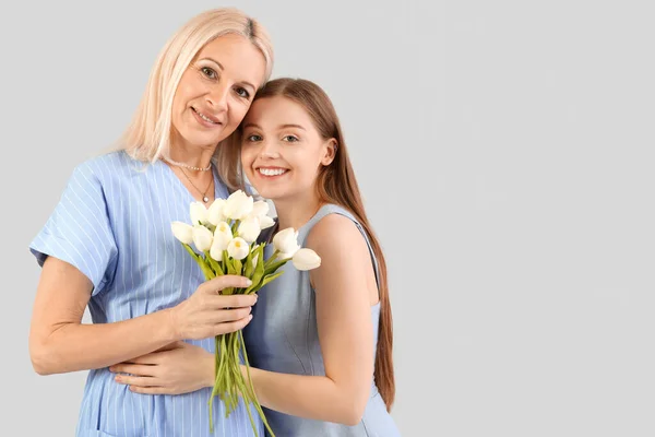 Giovane Donna Che Saluta Sua Madre Con Tulipani Sfondo Grigio — Foto Stock