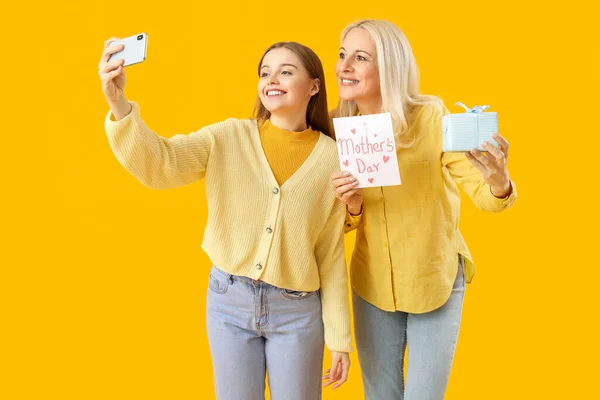 Young Woman Her Mother Gift Taking Selfie Orange Background — Stock Photo, Image