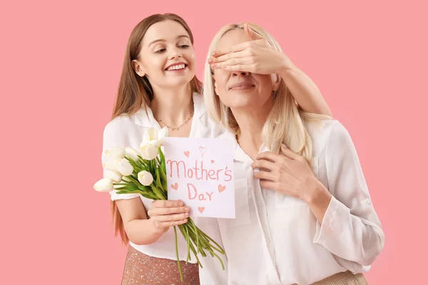 Mujer Joven Saludando Madre Con Tulipanes Tarjeta Sobre Fondo Rosa —  Fotos de Stock