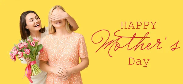 黄色の背景に花の花束を持つ美しい女性と彼女の娘 母の日のお祝い — ストック写真