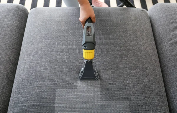 Woman removing dirt from sofa at home, top view