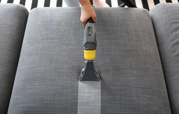 Woman removing dirt from sofa at home, top view