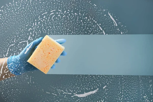 Hand with sponge washing window
