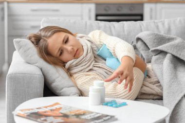 Ill girl with hot water bottle lying on sofa at home