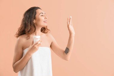 Genç esmer kadın pembe arka planda kozmetik krem kavanozuyla