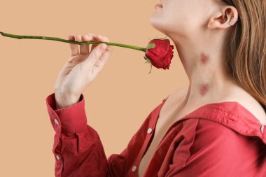 Young woman with love bites on her neck holding rose flower against color background, closeup clipart