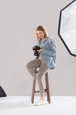 Profesyonel kameralı kadın fotoğrafçı stüdyoda oturuyor.