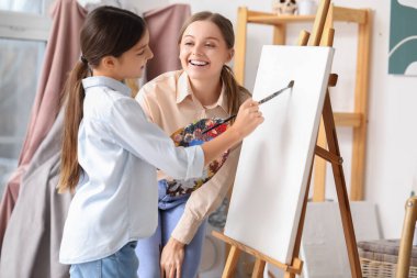 Resim öğretmeni atölyenin yanındaki küçük kıza özel resim dersi veriyor.