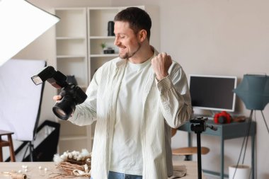 Stüdyoda profesyonel kamerası olan mutlu bir erkek fotoğrafçı.