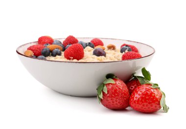 Beyaz arka planda yulaf ezmesi, olgun böğürtlen ve badem dolu bir kâse.