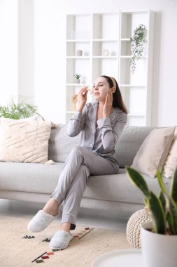 Maskeli genç bir kadın evde yüzüne masaj yapıyor.