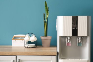 Mavi duvarın yanında modern su soğutuculu mutfağın içi.