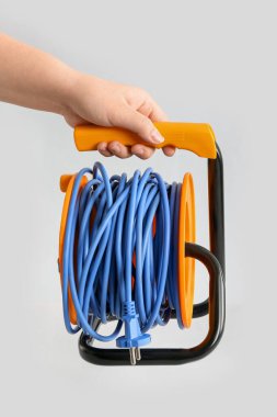 Uzatılmış elektrik kablosu olan kadın el beyaz arka planda izole edilmiş.