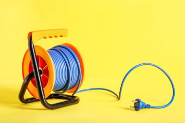 Sarı arkaplanda uzatmalı elektrik kablosu makarası