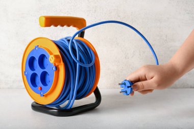 Genişletilmiş elektrikli kablo makaralı bir kadın el.