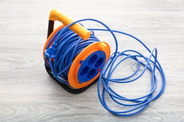 Genişletilmiş elektrikli kablo makarası açık ahşap arka planda