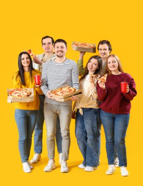 Sarı arka planda lezzetli pizza ve içecekler olan bir grup arkadaş.