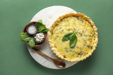 Lezzetli kiş, kulübe, tuz ve yeşil arka planda ıspanak yaprakları.