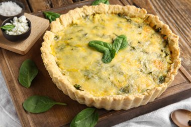 Lezzetli kiş ve kahverengi ahşap arka planda ıspanak yaprakları.