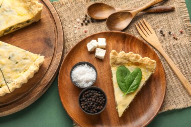 Bir parça lezzetli kiş ve yeşil arka planda baharatlar.