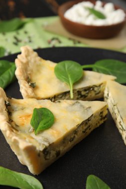 Siyah ahşap arka planda lezzetli kiş parçalarıyla dolu bir tabak.