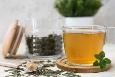 Açık arkaplanda bir fincan sıcak yeşil çay