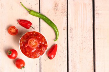 Bir kase lezzetli salsa sosu ve beyaz ahşap masadaki malzemeler.