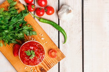 Lezzetli salsa sosu ve beyaz ahşap masadaki malzemelerle dolu bir masa.