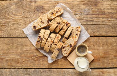 Lezzetli bisküviler, bir fincan kahve ve sürahi, ahşap arka planda.