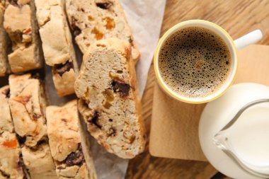 Lezzetli bisküviler, bir fincan kahve ve sürahi, ahşap arka planda.