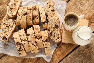 Lezzetli bisküviler, bir fincan kahve ve sürahi, ahşap arka planda.