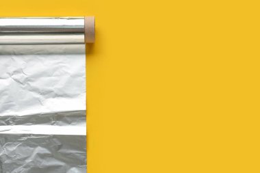 Roll of aluminium foil on yellow background