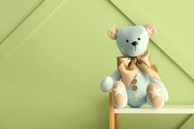Oyuncak ayı rafta, yeşil duvarın yanında.