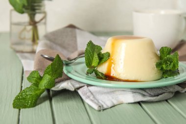 Lezzetli puding tabağı ve yeşil ahşap masada karamel şurubuyla kaplı nane.