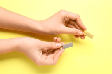 Sarı arka planda metalik ve altın USB flaş bellek tutan kadın eller