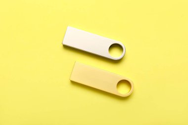 Sarı arka planda metalik ve altın USB flaş bellekler