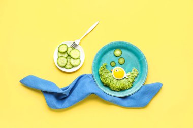 Sarı zemin üzerinde balık ve sebze şeklinde komik bir kahvaltı tabağı.