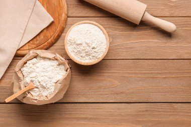 Tahta masaya bir kase un, torba ve oklavayla kompozisyon.