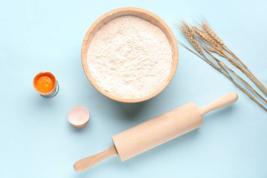 Unlu kase, buğday kulaklı, kırık yumurta ve mavi arka planda merdane.