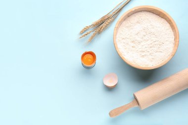 Unlu kase, buğday kulaklı, kırık yumurta ve mavi arka planda merdane.