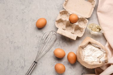 Gri grunge masa üzerinde çuval dolusu un, yumurta ve çırpma.