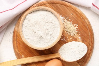 İçinde buğday unu, susam tohumu, beyaz grunge masasında kaşık ve yumurta var.