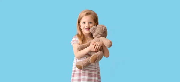Funny little girl with teddy bear on light blue background