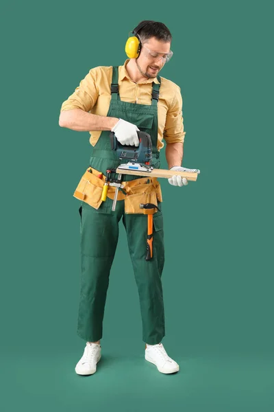 Homem Carpinteiro Serrar Prancha Madeira Com Quebra Cabeça Fundo Verde — Fotografia de Stock