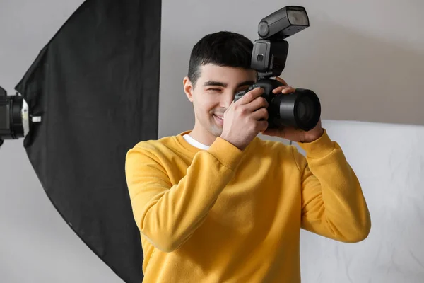 持有专业相机的年轻男性摄影师在演播室工作 — 图库照片