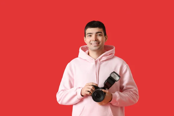 若いです男性写真家とともにプロのカメラ上の赤い背景 — ストック写真