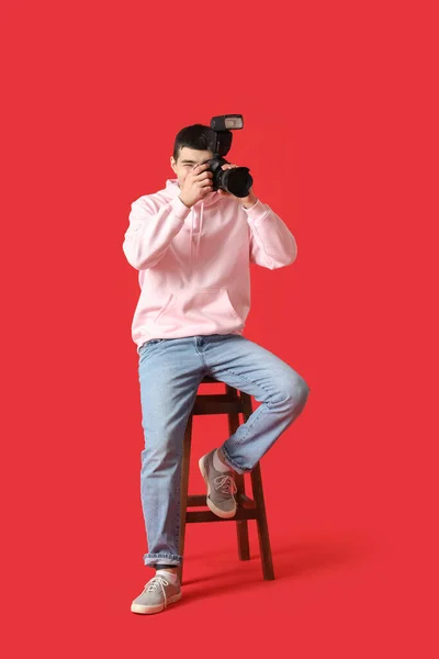 Jonge Mannelijke Fotograaf Met Professionele Camera Zittend Rode Achtergrond — Stockfoto