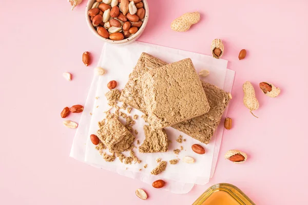 stock image Tasty halva and peanuts on pink background